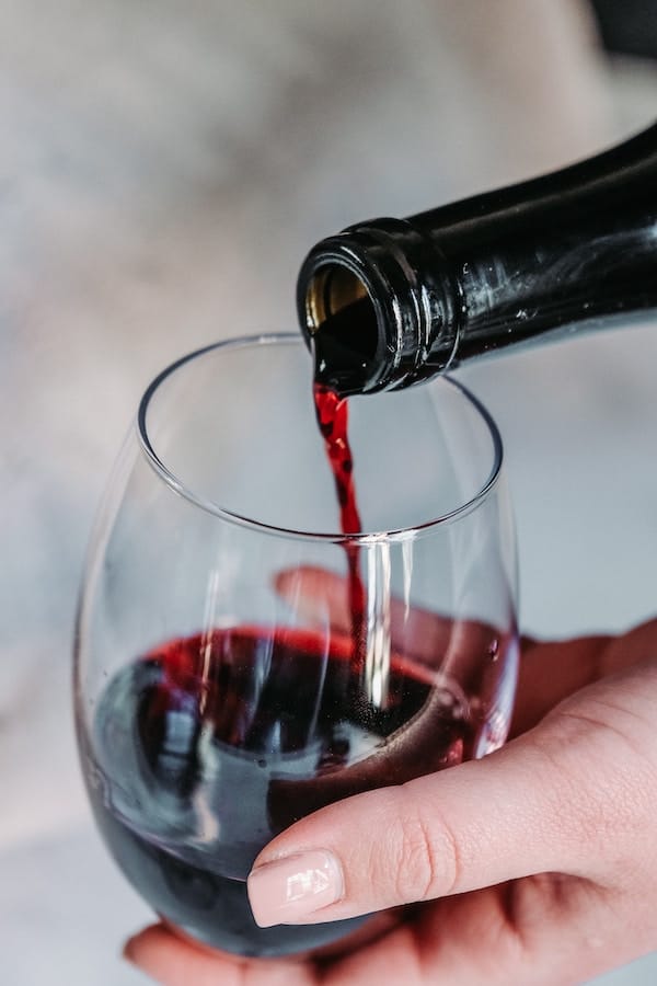 red wine being poured down into a wine glass
