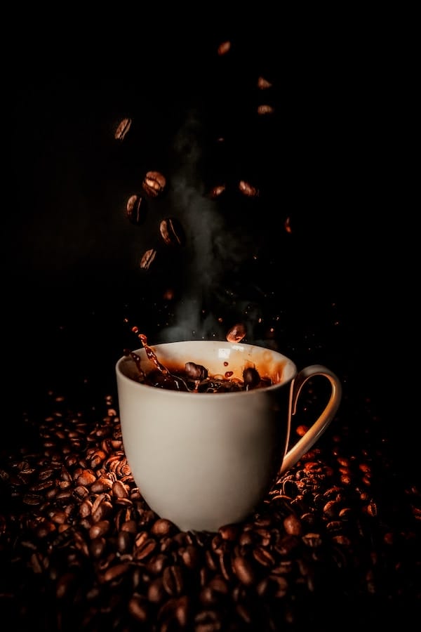 a cup of coffee on top of coffee beans