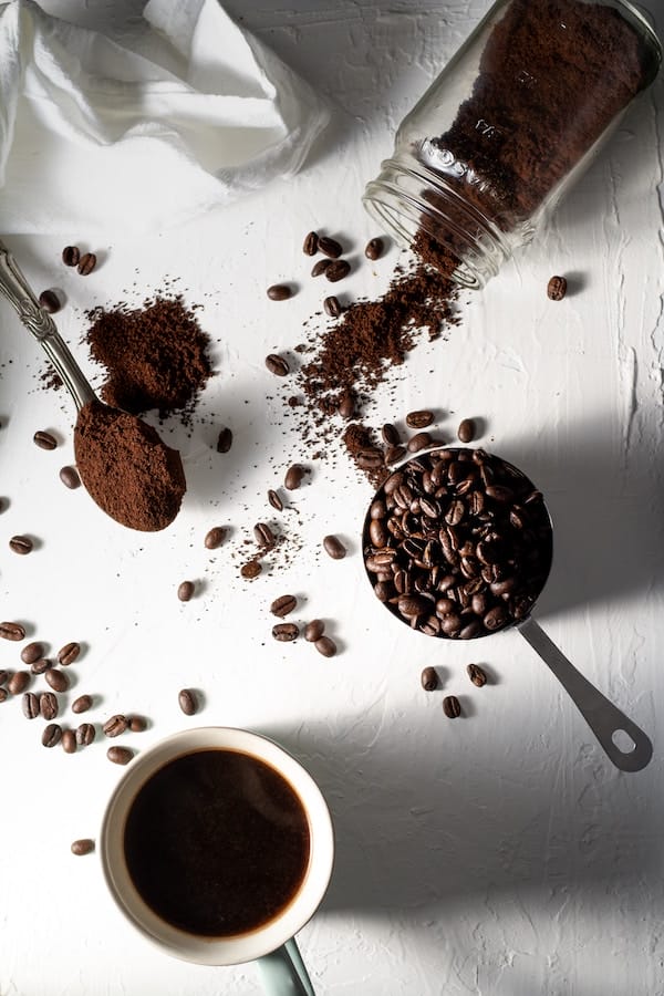 coffee beans and ground cofee on a white surface