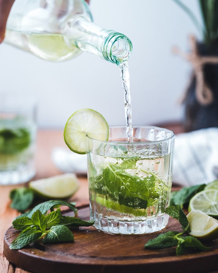 a cocktail, mojito, being poured into a glass