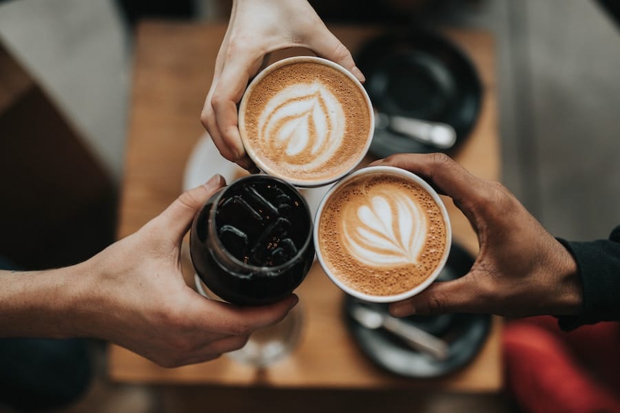 three people tossing together 3 cups of coffee