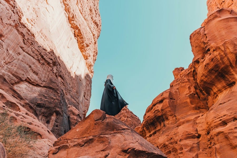 a man on top of rocks in a desert, illustrating slow travel