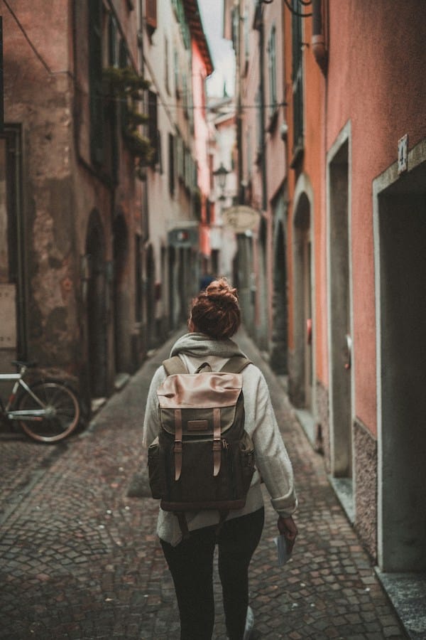 a woman walking in a old town with a backpack, illustrating slow travel